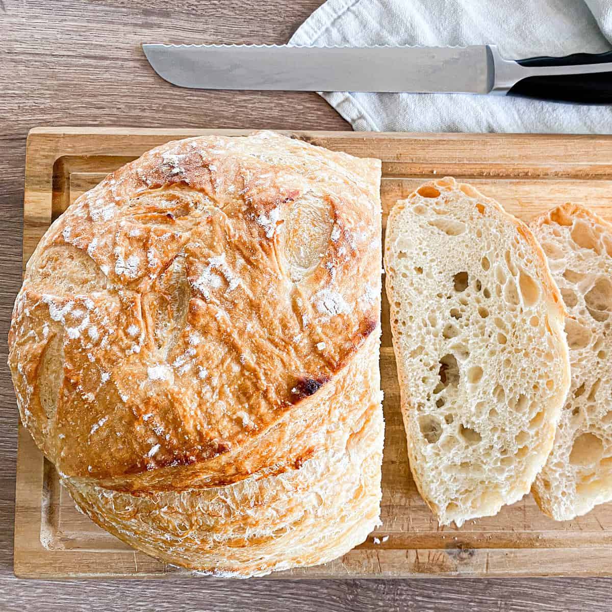 Artisan Sourdough Bread on a wooden cutting board, three slices are displayed on the cutting board