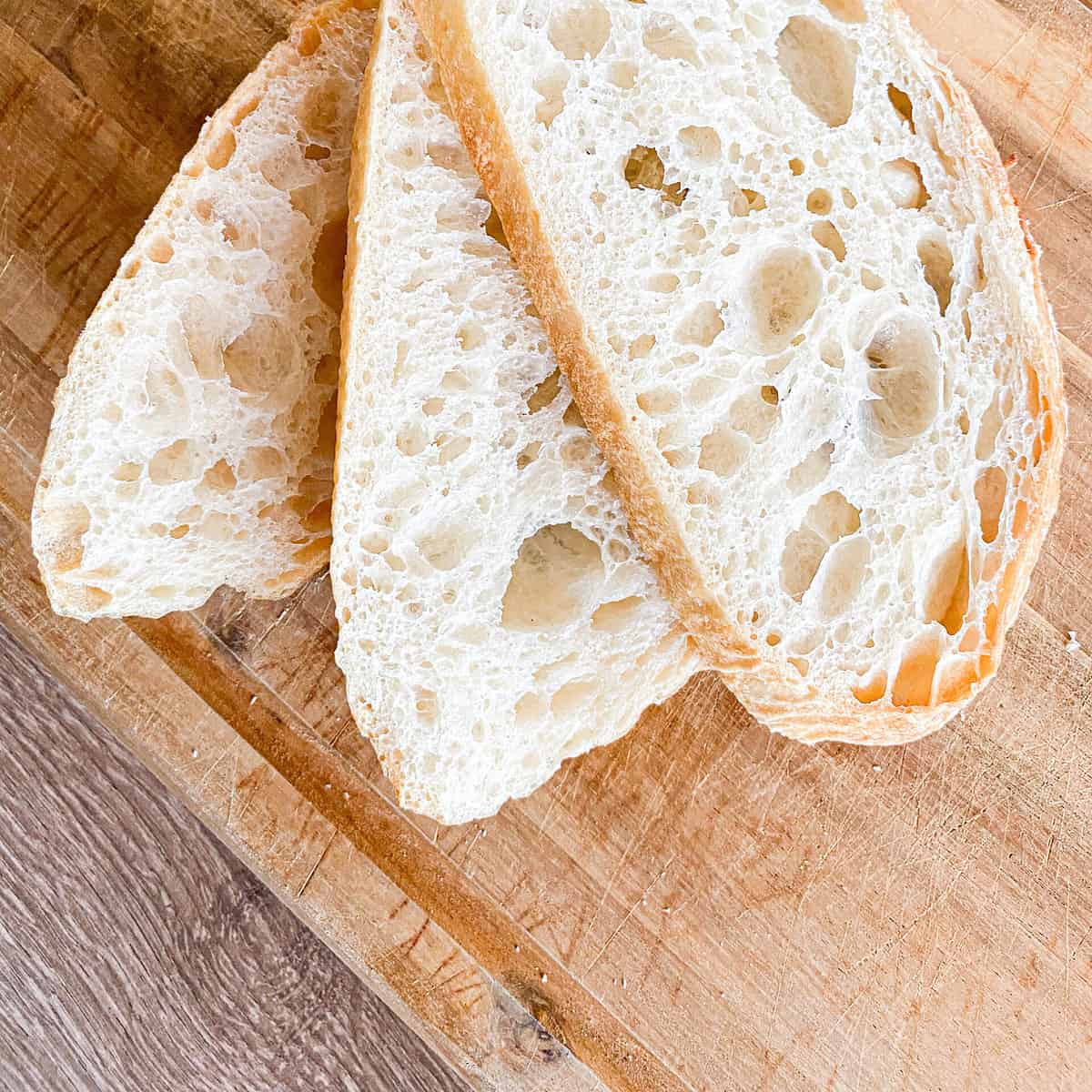 three slices of artisan Sourdough Bread on a wooden cutting board, showing a nice crumb structure