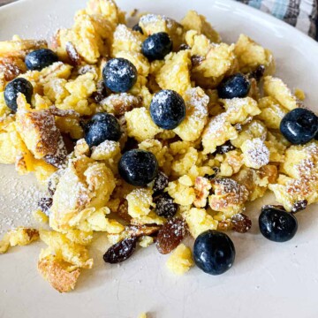 Sourdough Kaiserschmarrn or Shredded Austrian Pancake on a plate with fresh blueberries on top.