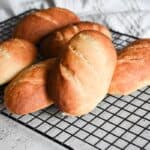 Soft sourdough sandwich rolls cooling on a wire rack.