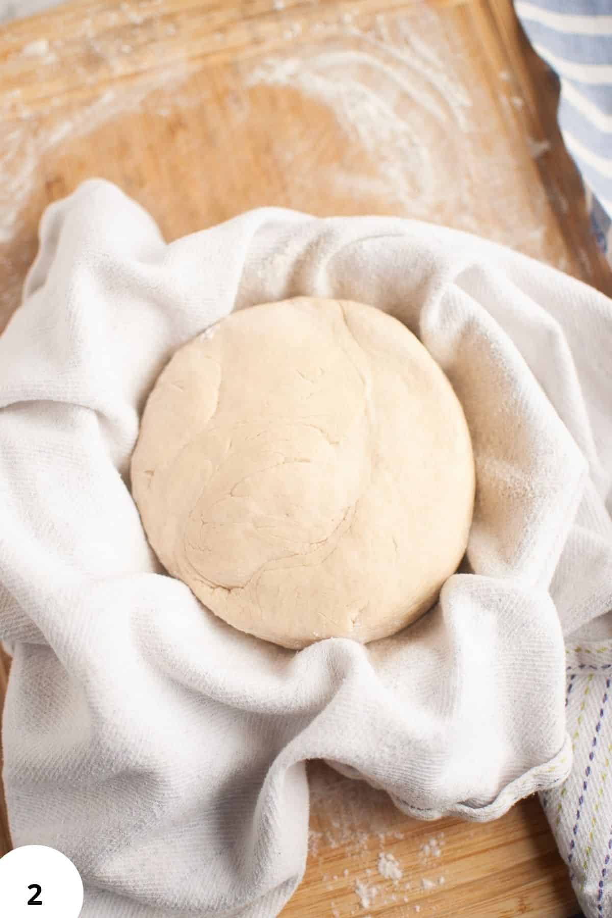 Sourdough bread dough during stretch and fold process on a floured surface.