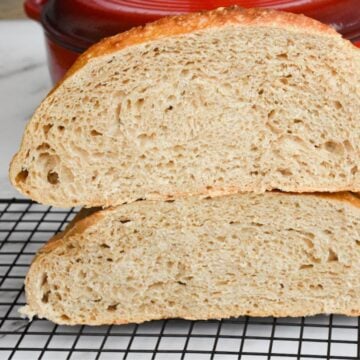 Artisan sourdough bread on a cooling rack, showing the crumb because it is cut in half.