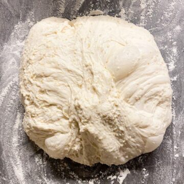 Sourdough bread dough with quinoa on a floured counter top.