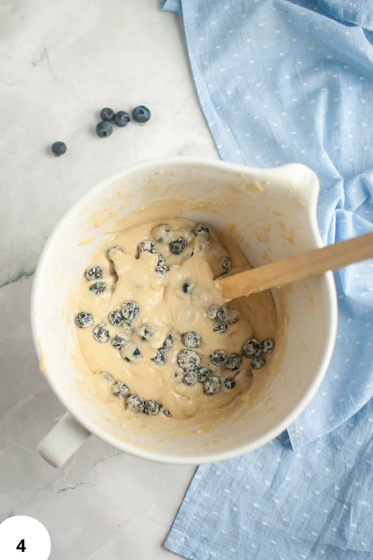 Blueberry and lemon quick bread dough being mixed in a bowl with blueberries.