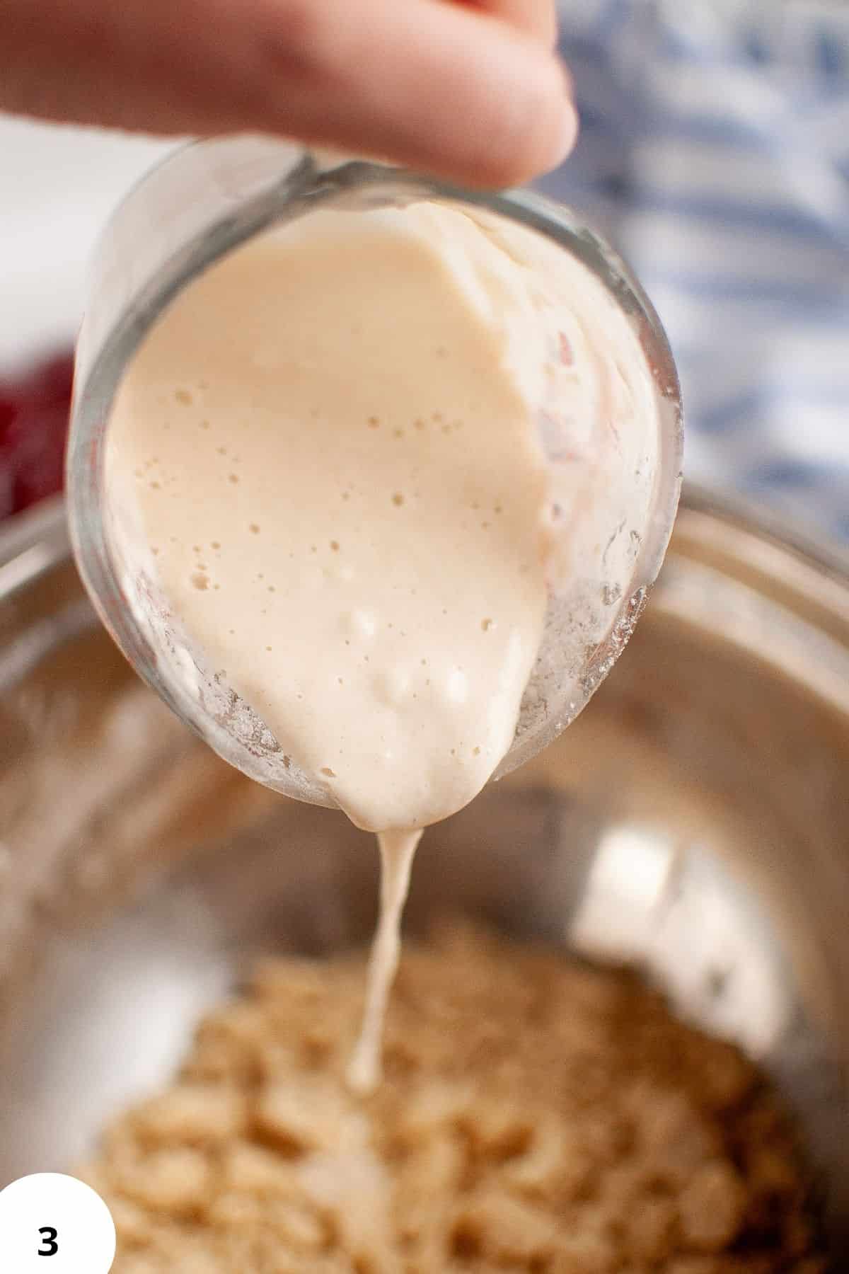 Pouring creamy filling into sourdough hand pies for jam-filled treats.