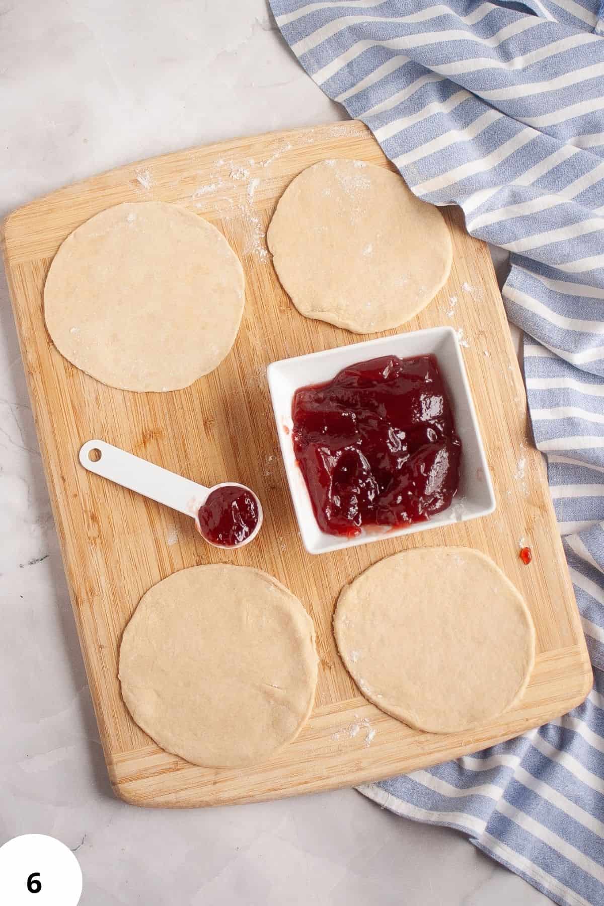 Preparing sourdough hand pies with jam filling on a wooden board.