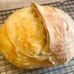 Loaf of sourdough bread on a cooling wire rack.