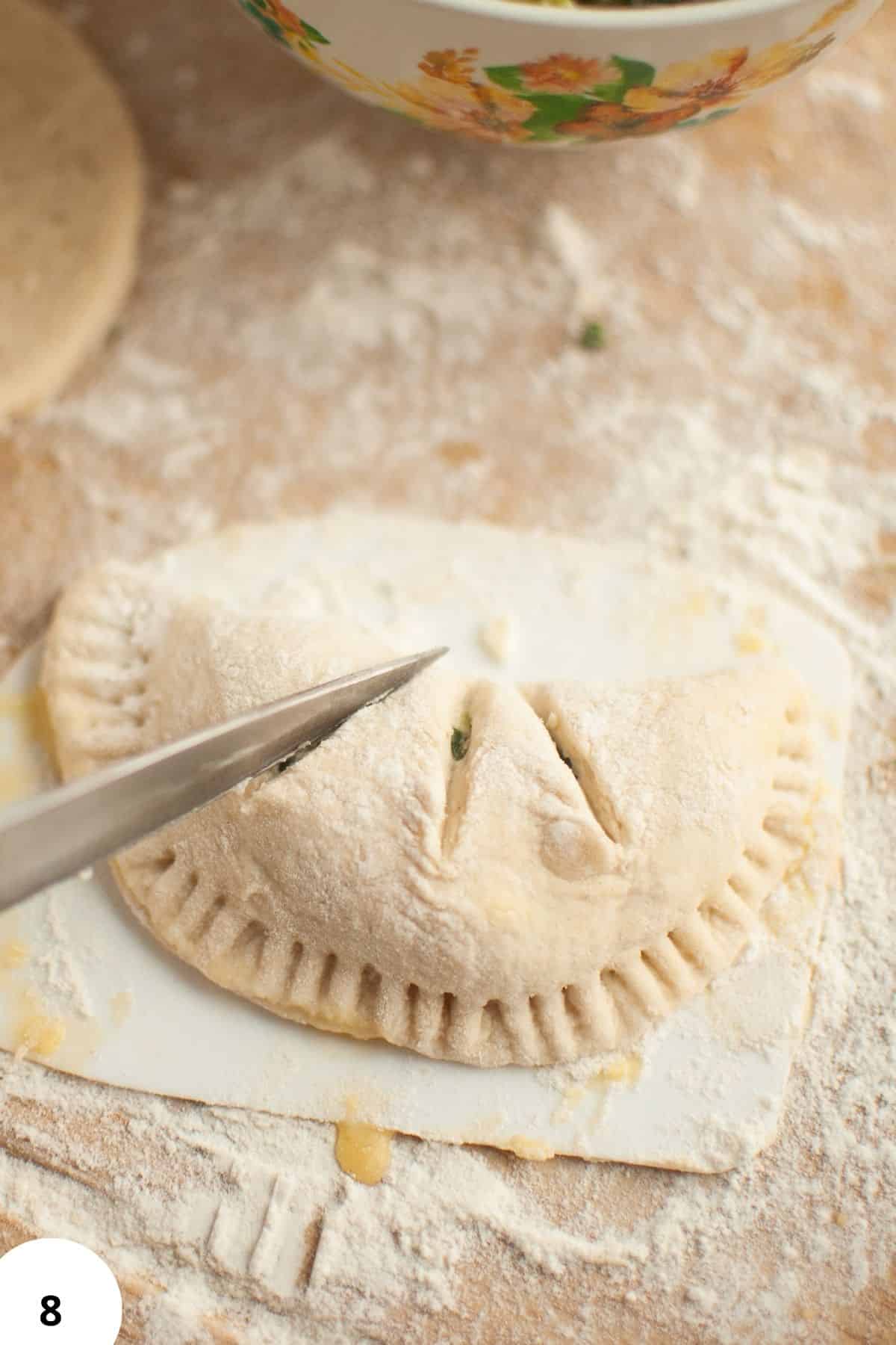 Hand pie filled with spinach and feta cheese on floured surface for sourdough baking.