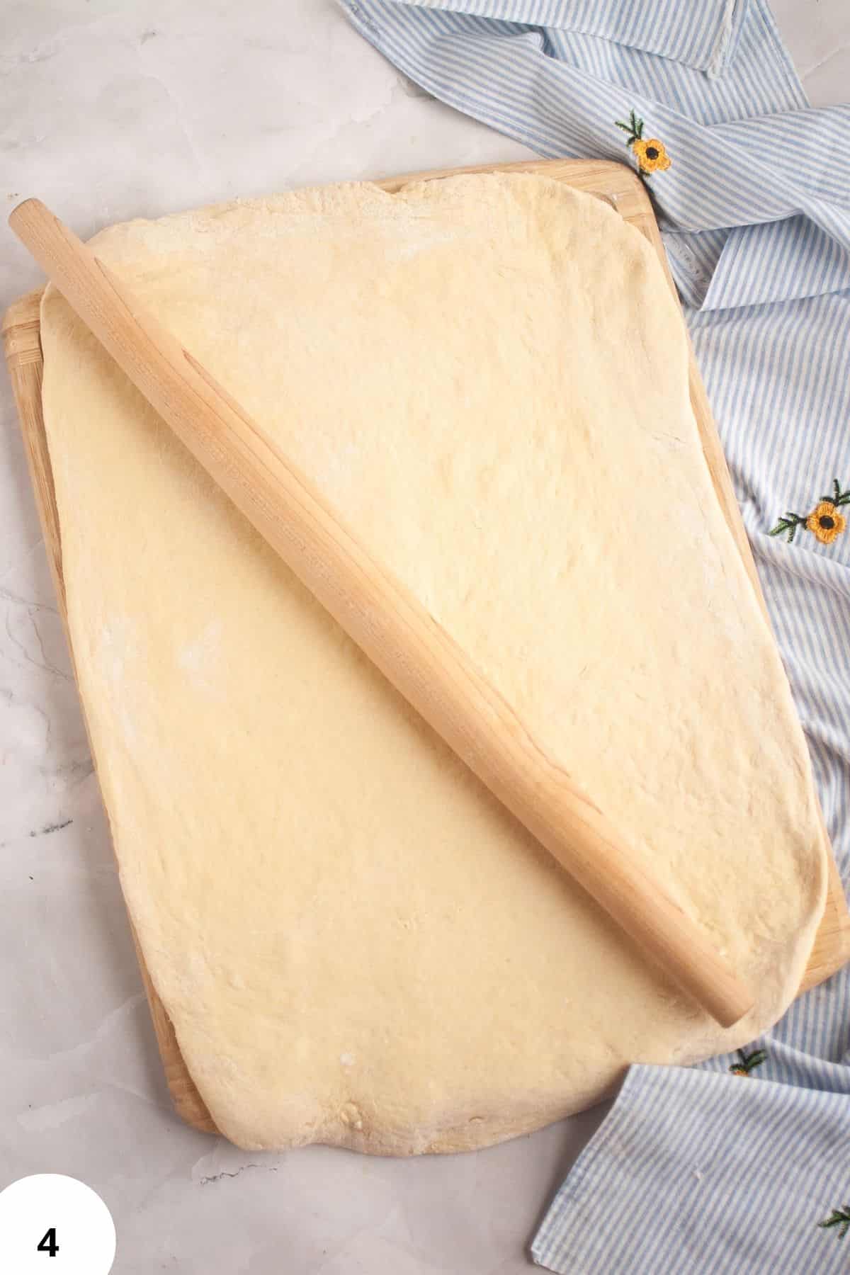 Sourdough dough being stretched and folded on a wooden surface.
