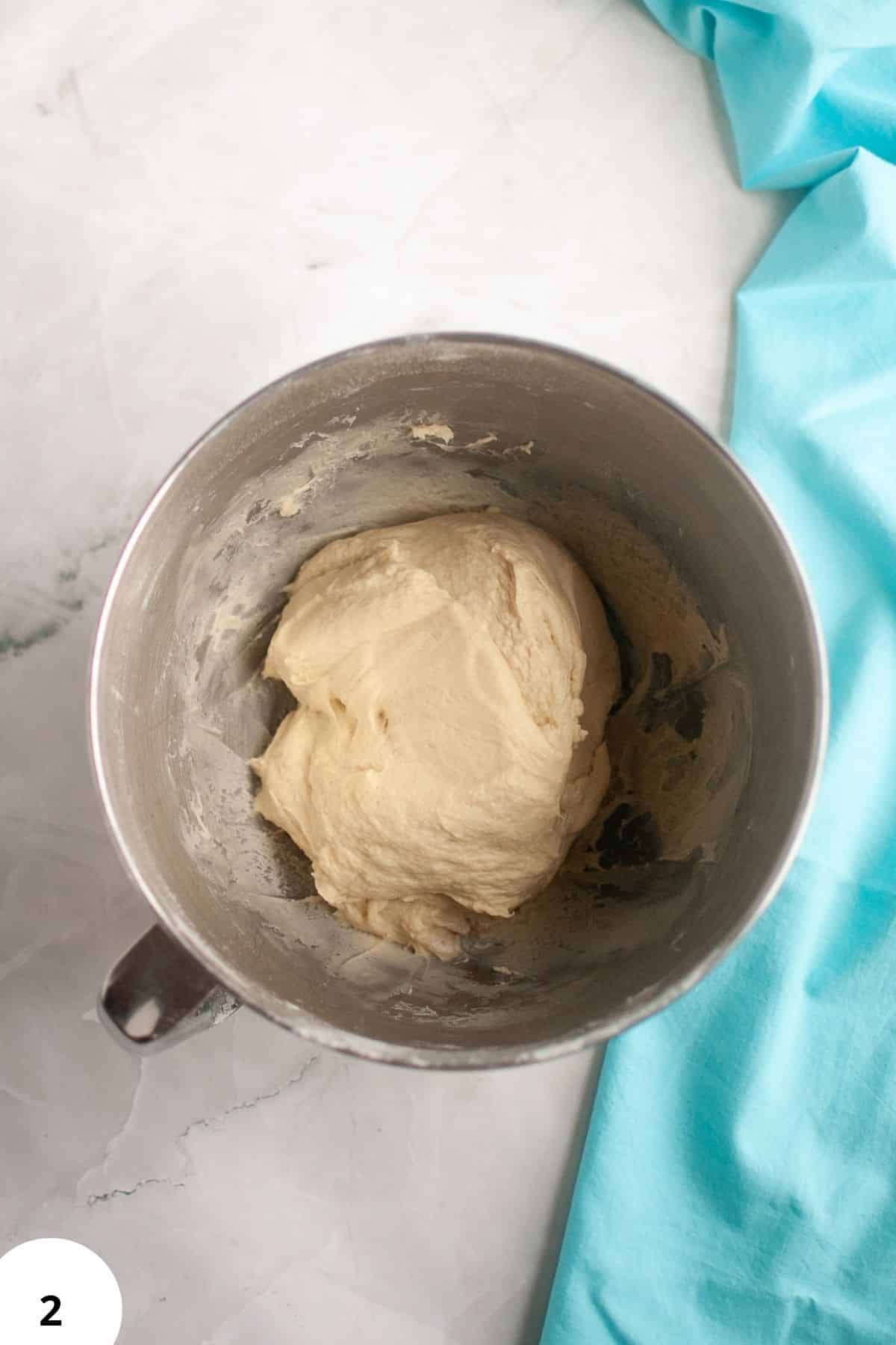 Dough ball in mixing bowl for bread baking, ready for folding and shaping.