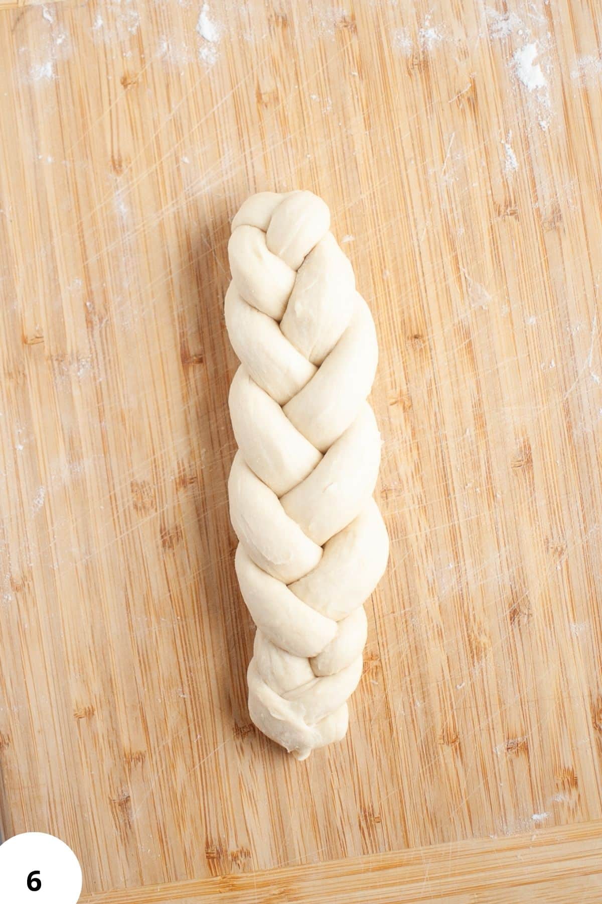 Braided dough for bread on wooden surface, demonstrating stretch and fold technique.
