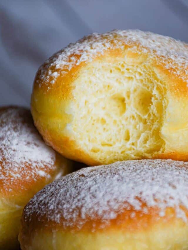 Sourdough bomboloni doughnuts, one with a bite in it.