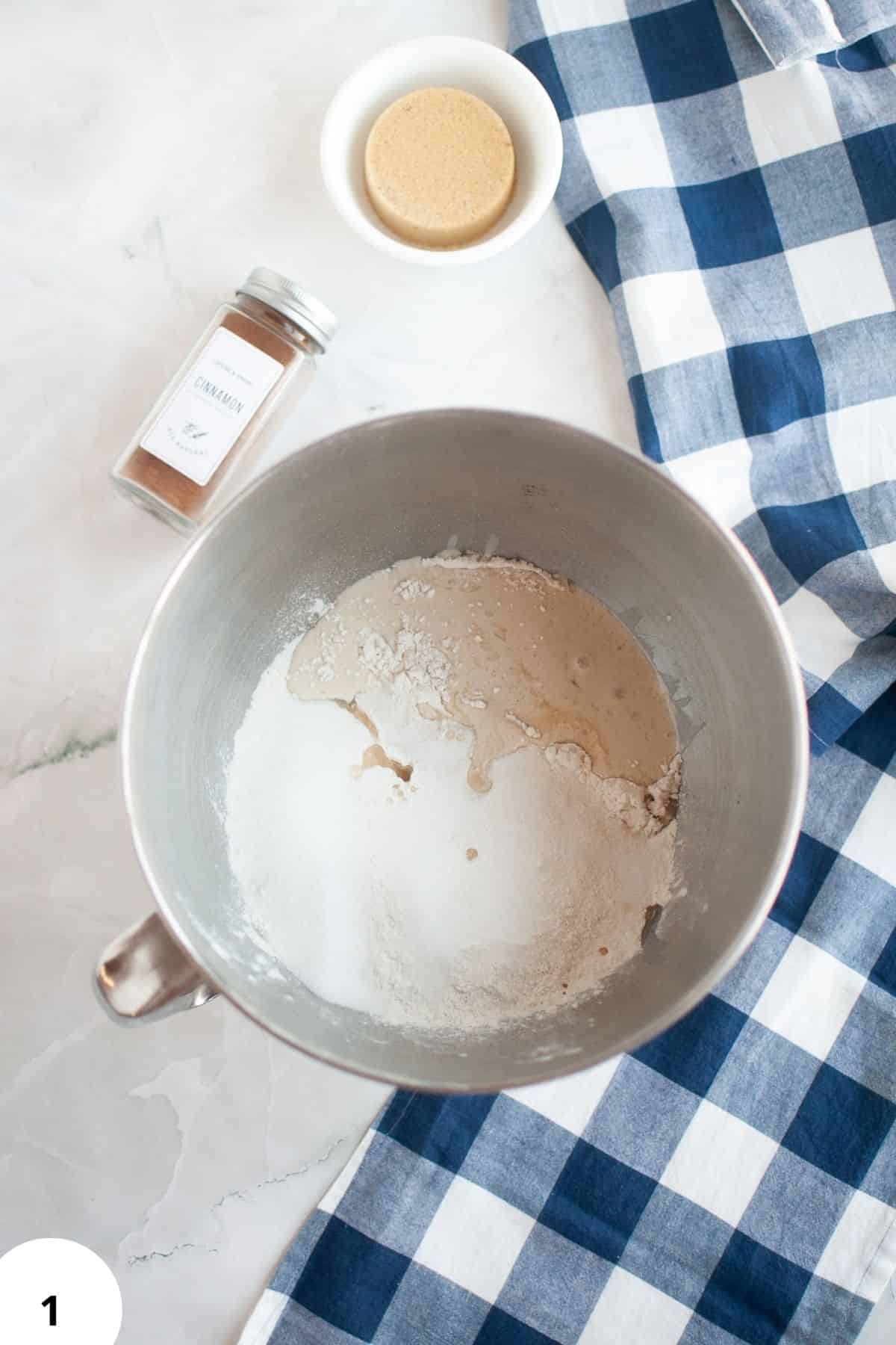 Dough in mixing bowl with yeast, sugar, and water for bread fermentation.