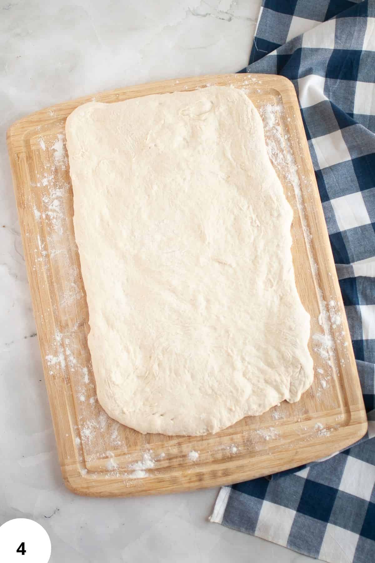 Raw dough on a wooden board ready for stretching and folding in bread baking.