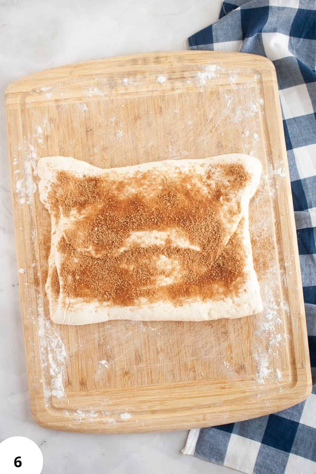Freshly shaped bread dough on a wooden board with flour, ready for proofing or baking.