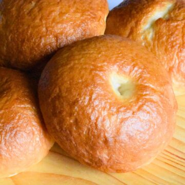 A golden brown sourdough bagel on a cutting board.