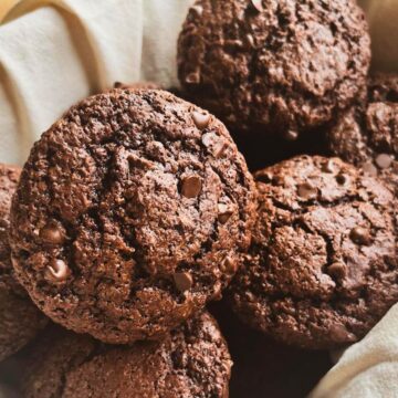 Double chocolate sourdough muffins in a tea towel lined basket.