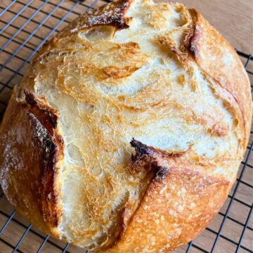 A loaf of bread on a black wire rack.