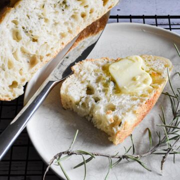 A piece of butter melting on a piece of freshly baked bread on a plate.