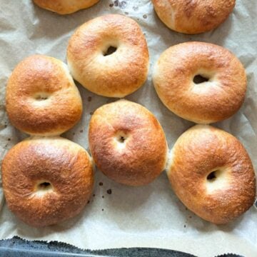 Sourdough bagels on a piece of parchment paper, right out of the oven.