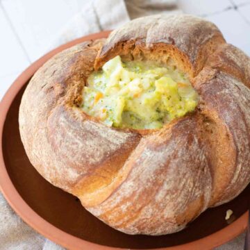 Close up photo of broccoli cheddar soup in a sourdough bowl.