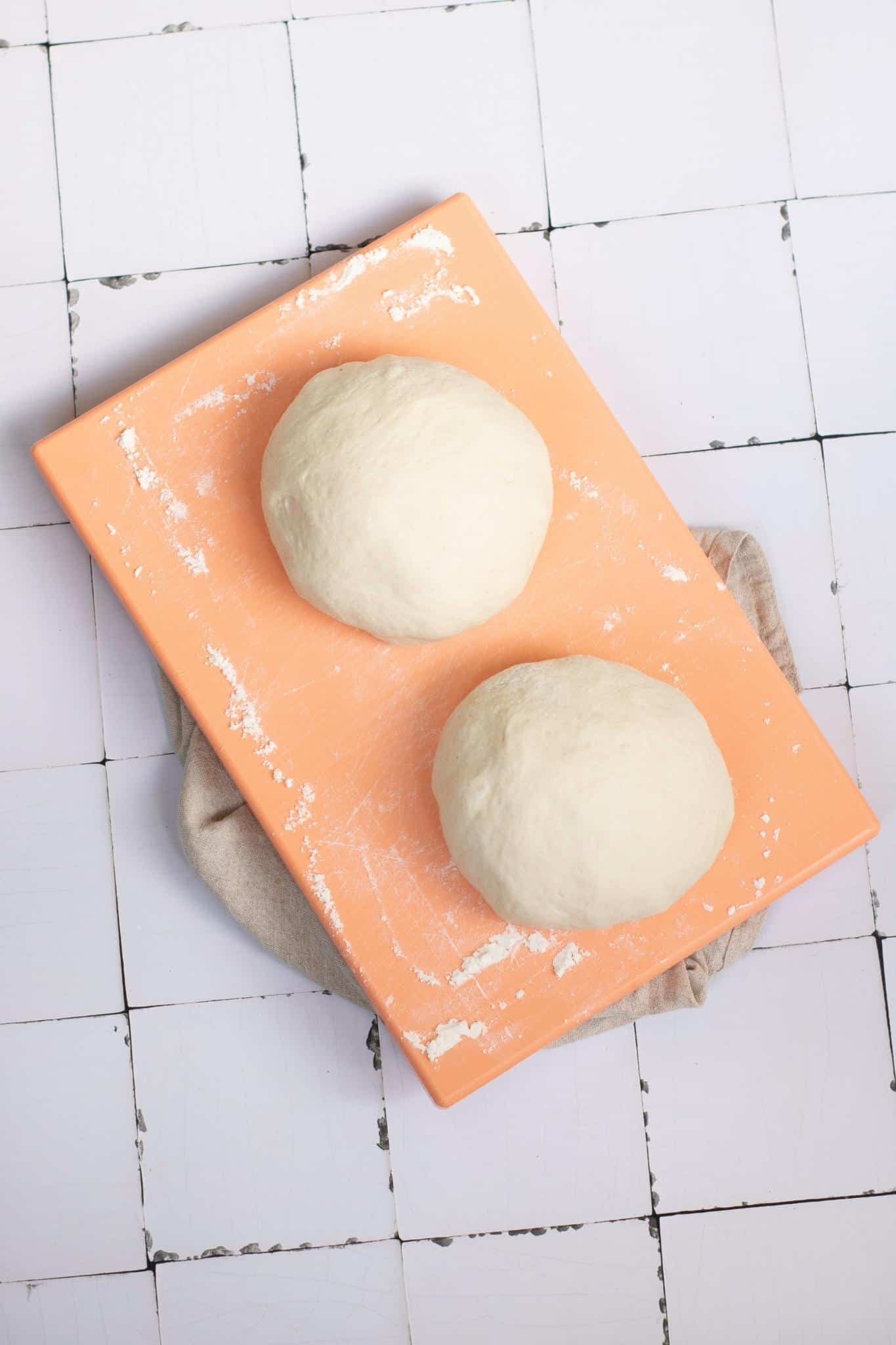 Two round shapes form dough in an orange board.