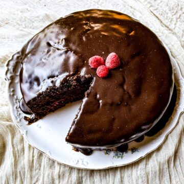 Garnished sourdough chocolate cake with one missing piece on a plate.