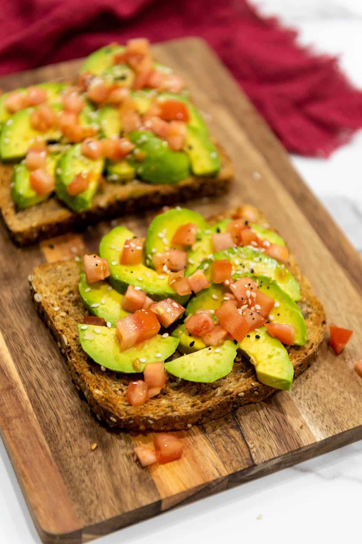 Avocado toast with sliced avocado, diced tomato, and seasoning on toasted bread.