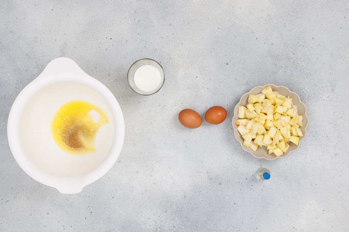 Ingredients for apple cinnamon muffins on a surface.
