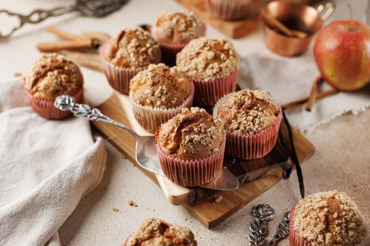 Apple cinnamon muffins being served on a wooden board.