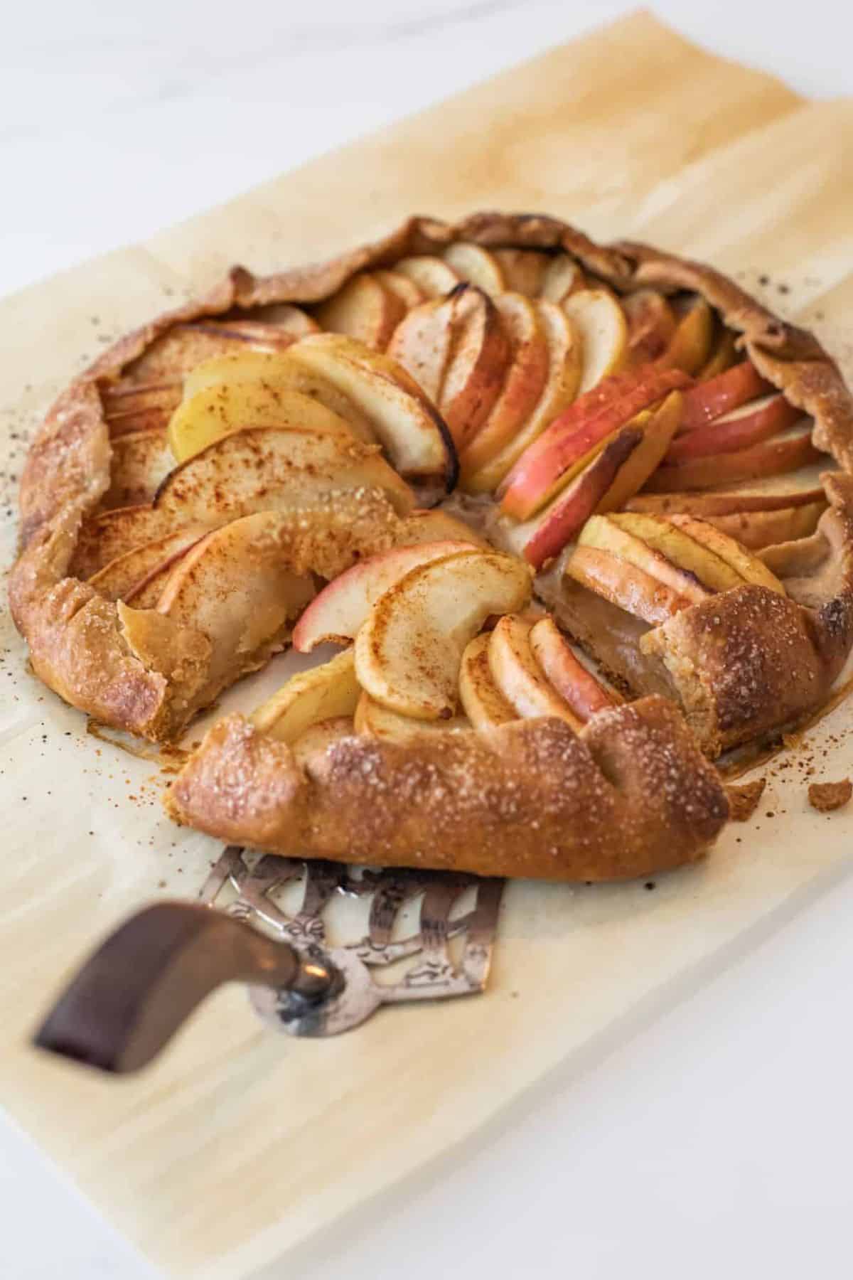 A slice of easy rustic apple galette on a plate with a cake scoop.