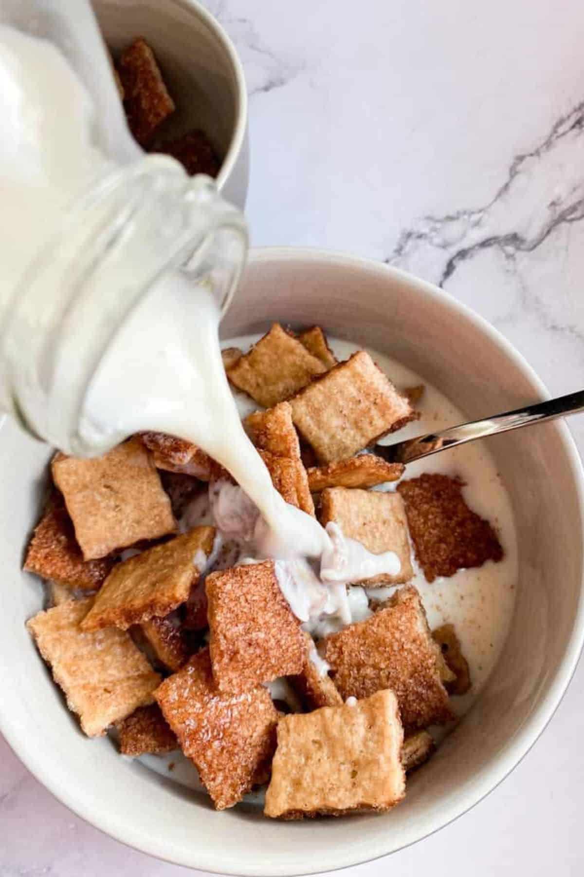 Close-up of milk being poured into a bowl of cereal.