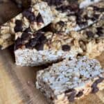 Granola bars arranged on a wooden board, showcasing their textured surface and chocolate chip topping.