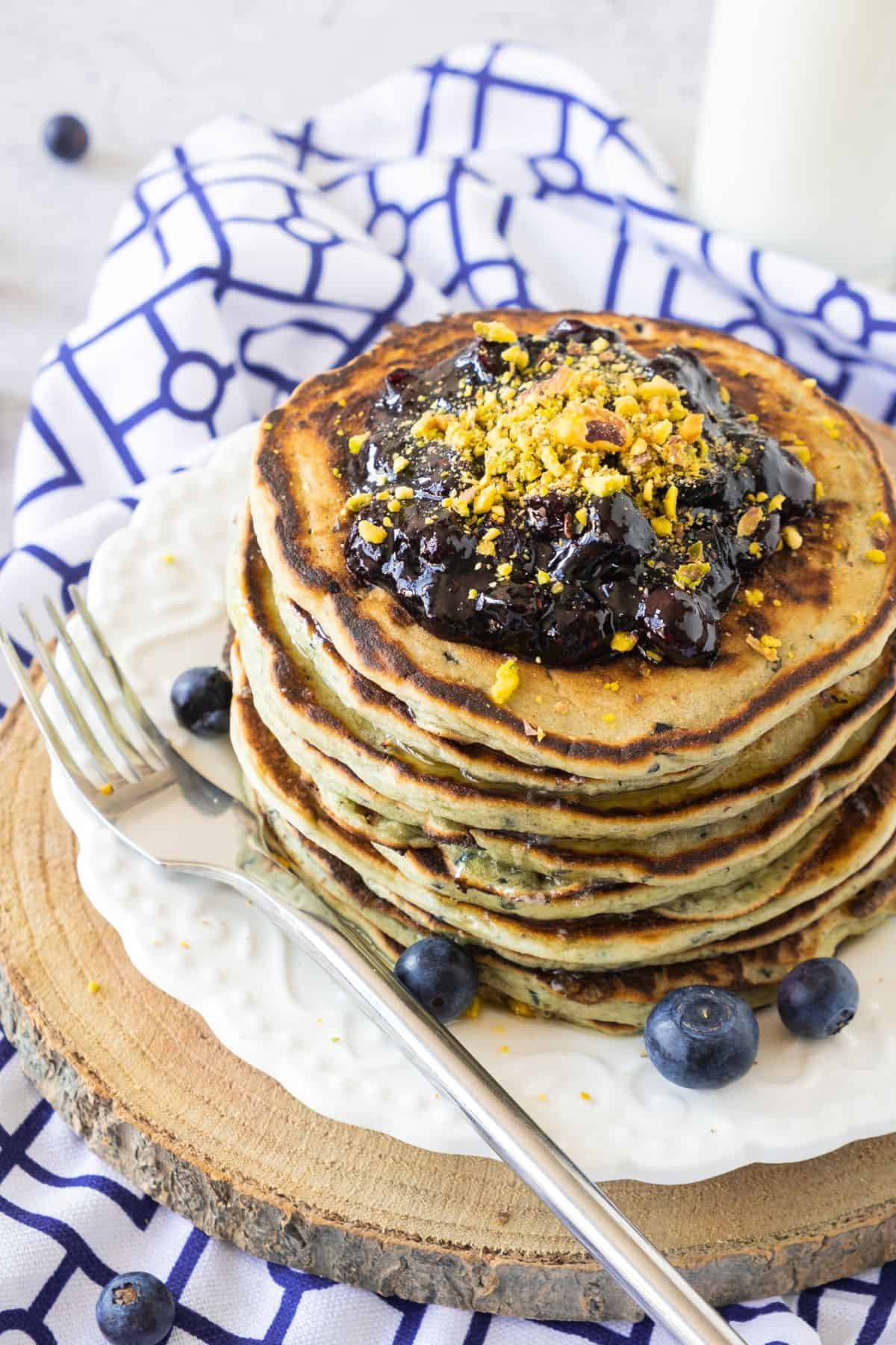 A stack of pancakes topped with blueberry jam.