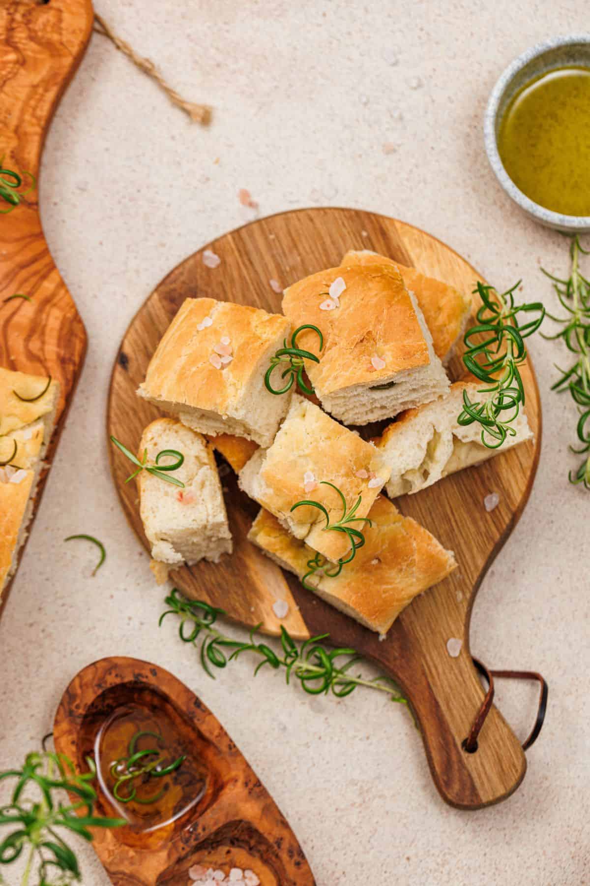 Square pieces of freshly baked focaccia served with balsamic vinegar on a wooden board.