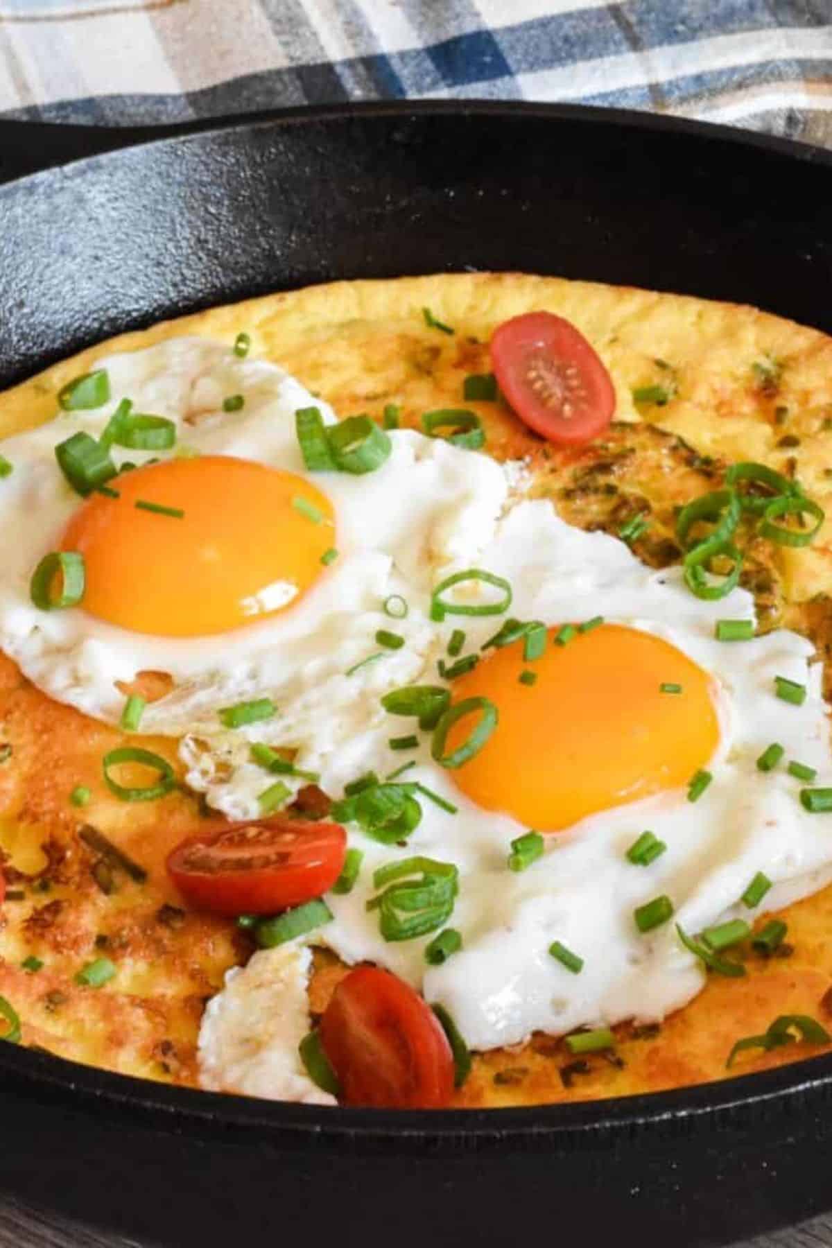 A golden-brown sourdough pancake topped with a sunny-side-up egg, served in a skillet.