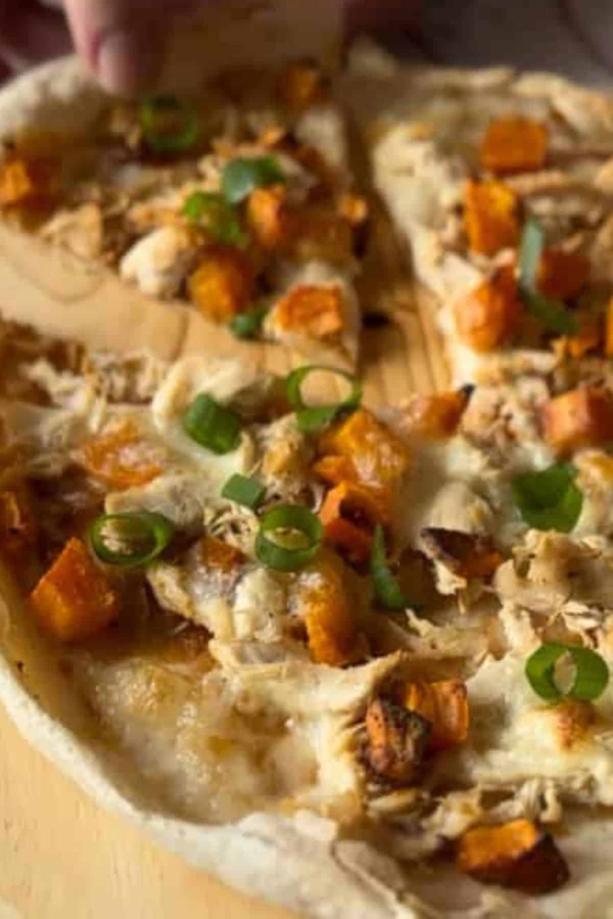 A whole pizza on a plate with one slice slightly separated from the rest, showing the toppings and baked crust.