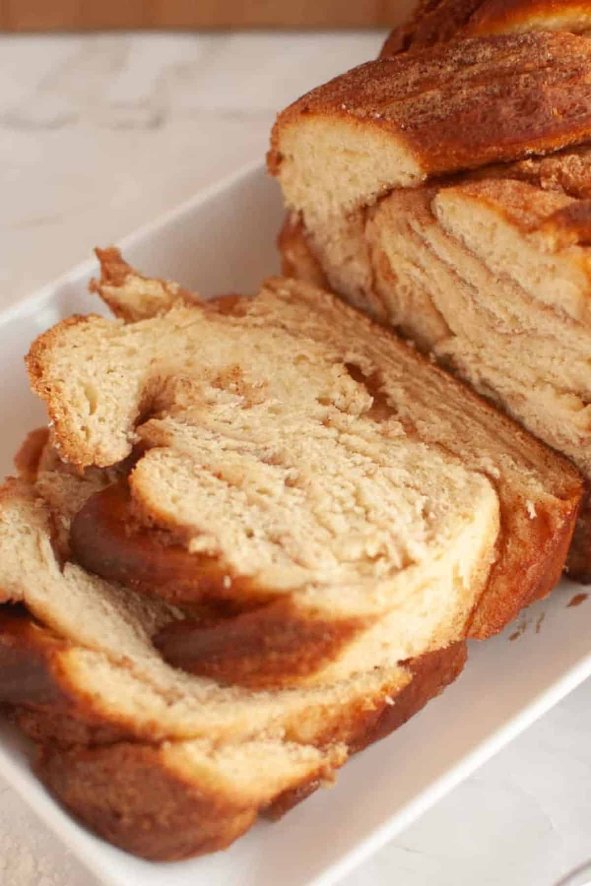 A sliced loaf of bread with another whole loaf nearby, both resting on a surface.