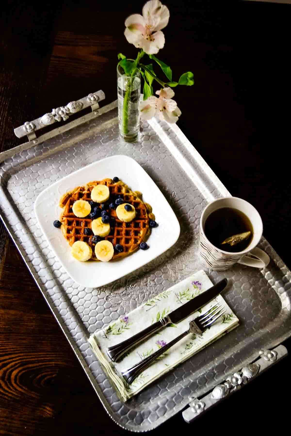 Waffle topped with fresh berries, served with a drink on the side.