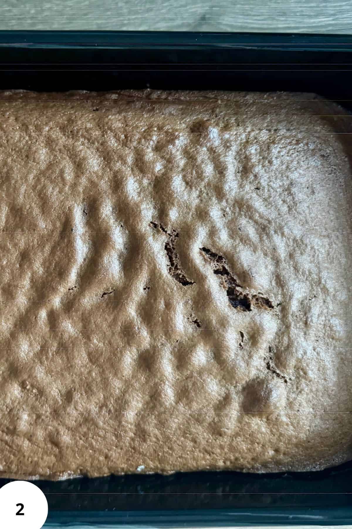 Freshly baked brown chocolate sponge cake in a rectangular pan.