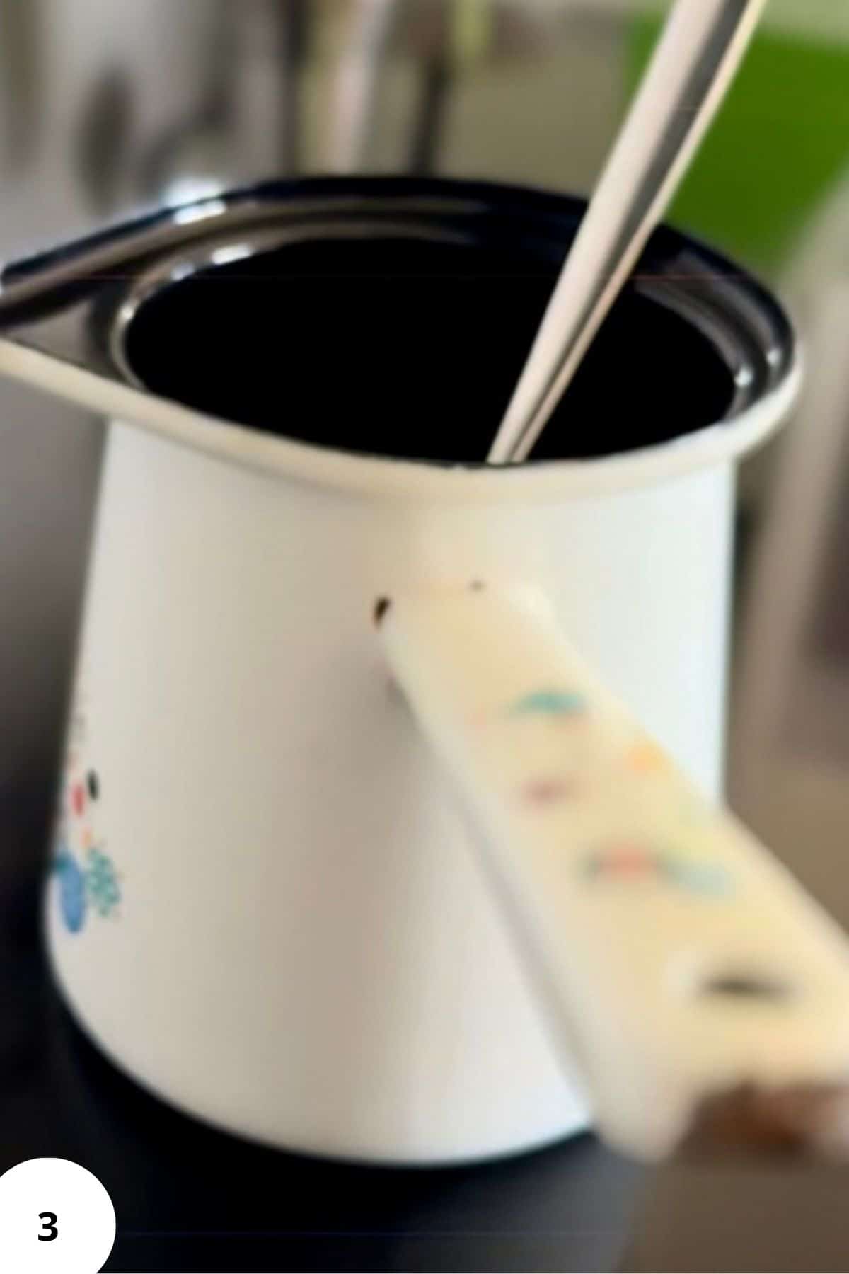 Mini ceramic pitcher with a spoon resting on the rim.
