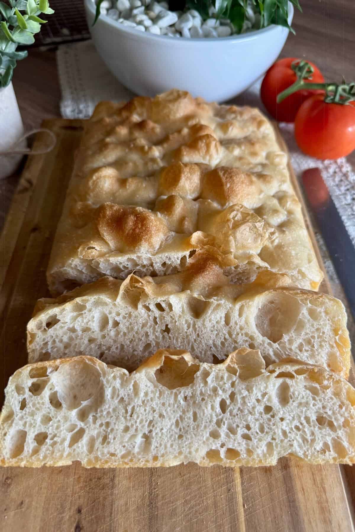 Sourdough focaccia being sliced, revealing its soft, airy interior and golden crust.