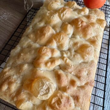 Freshly baked sourdough focaccia resting on a wire cooling rack.
