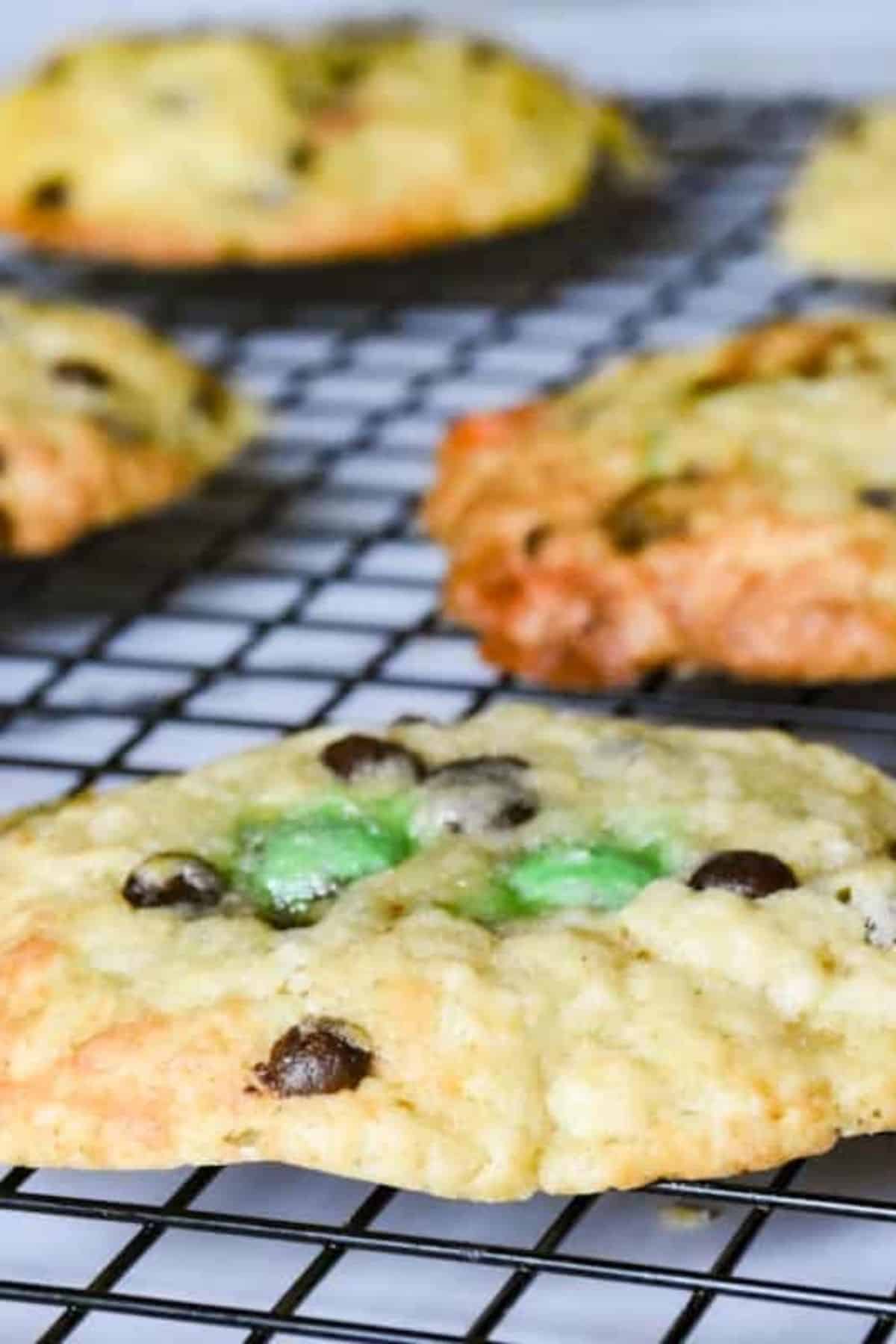 Freshly baked cookies with M&Ms visible on top, cooling on a wire rack.