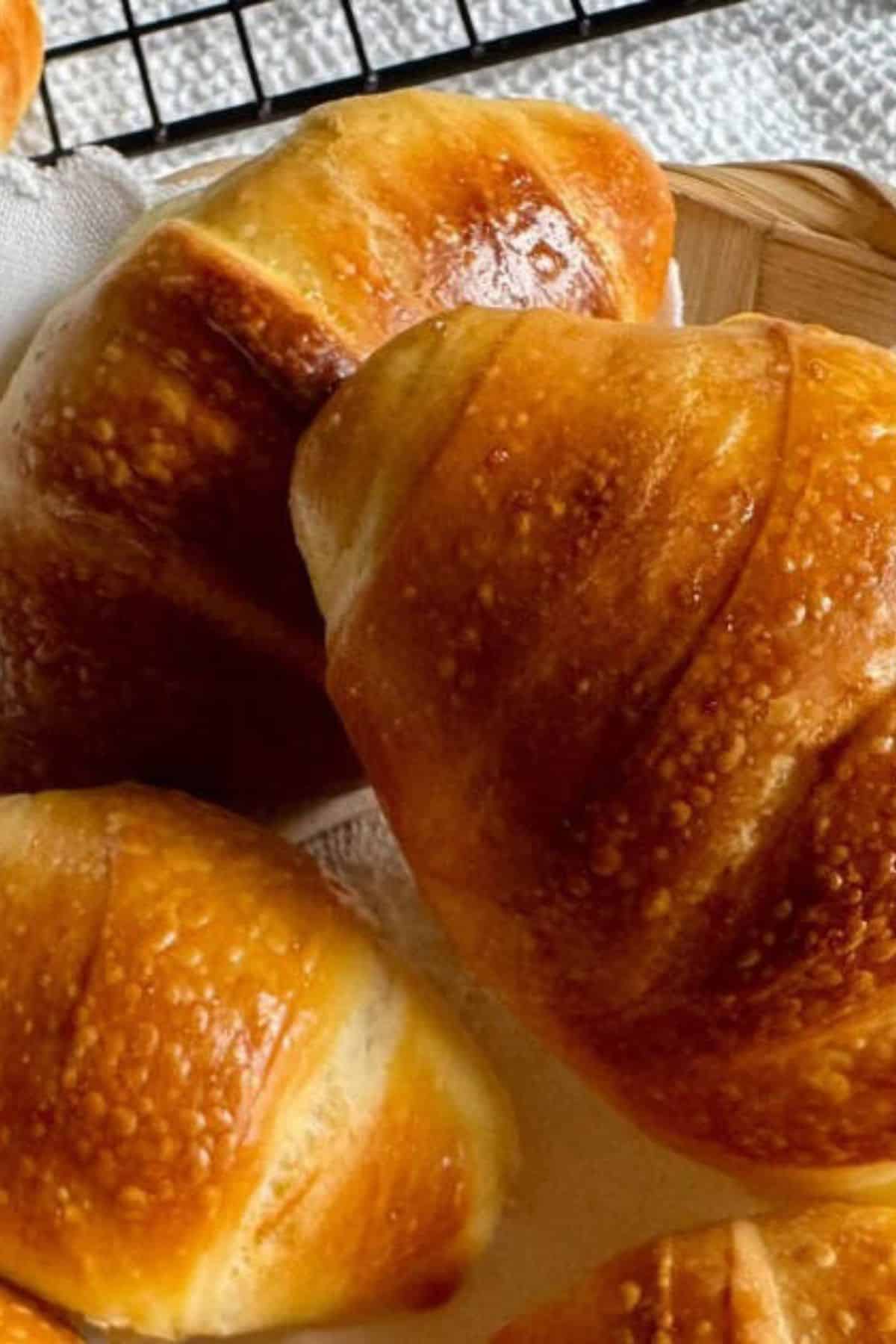 Close-up of soft, golden brown rolls with a shiny, glazed surface and fluffy texture.