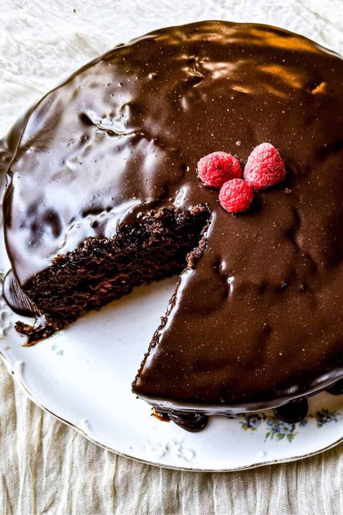 Chocolate cake topped with raspberries being sliced with a knife.