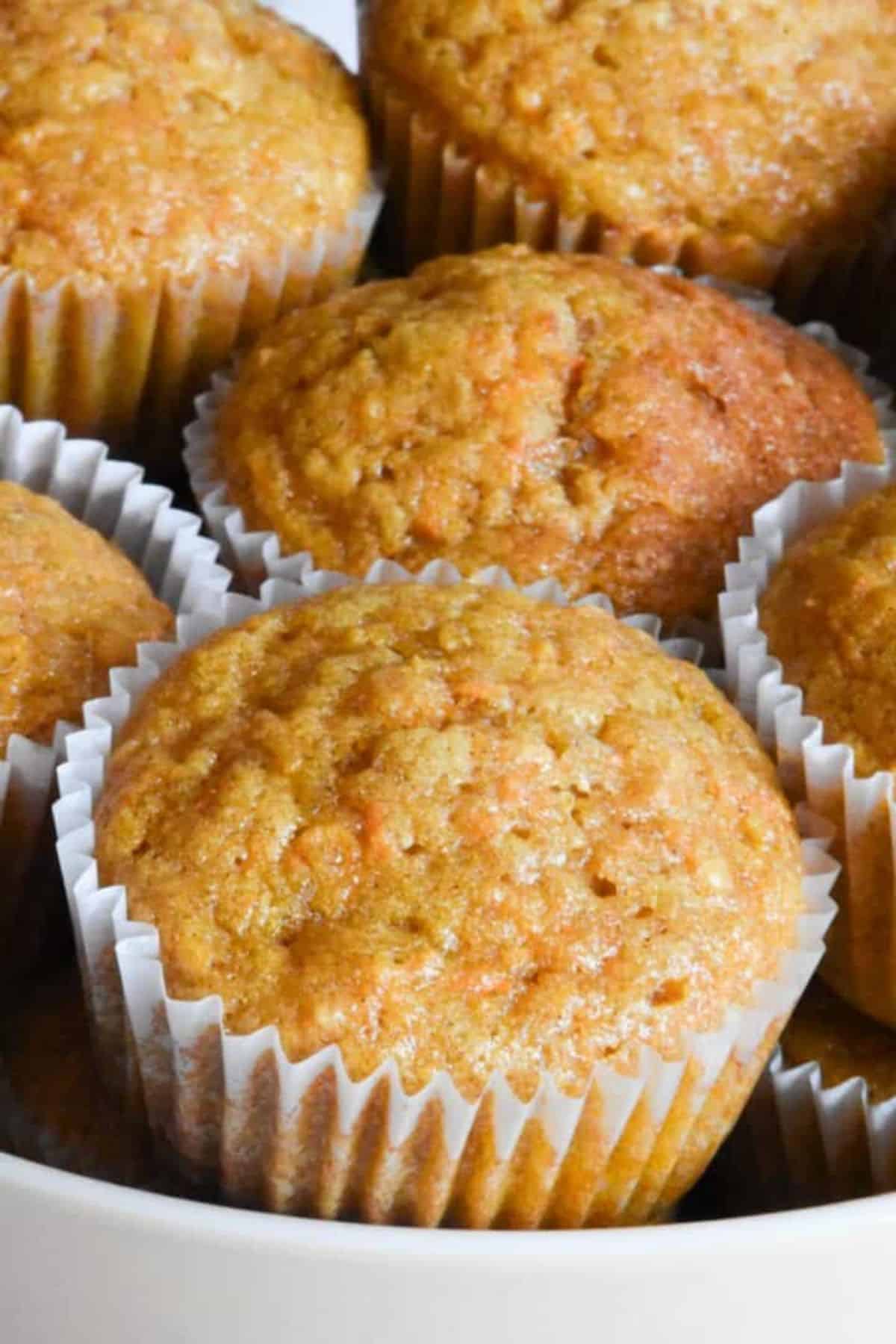 Close-up of sourdough carrot cake muffins with visible shreds of carrot and a moist crumb.