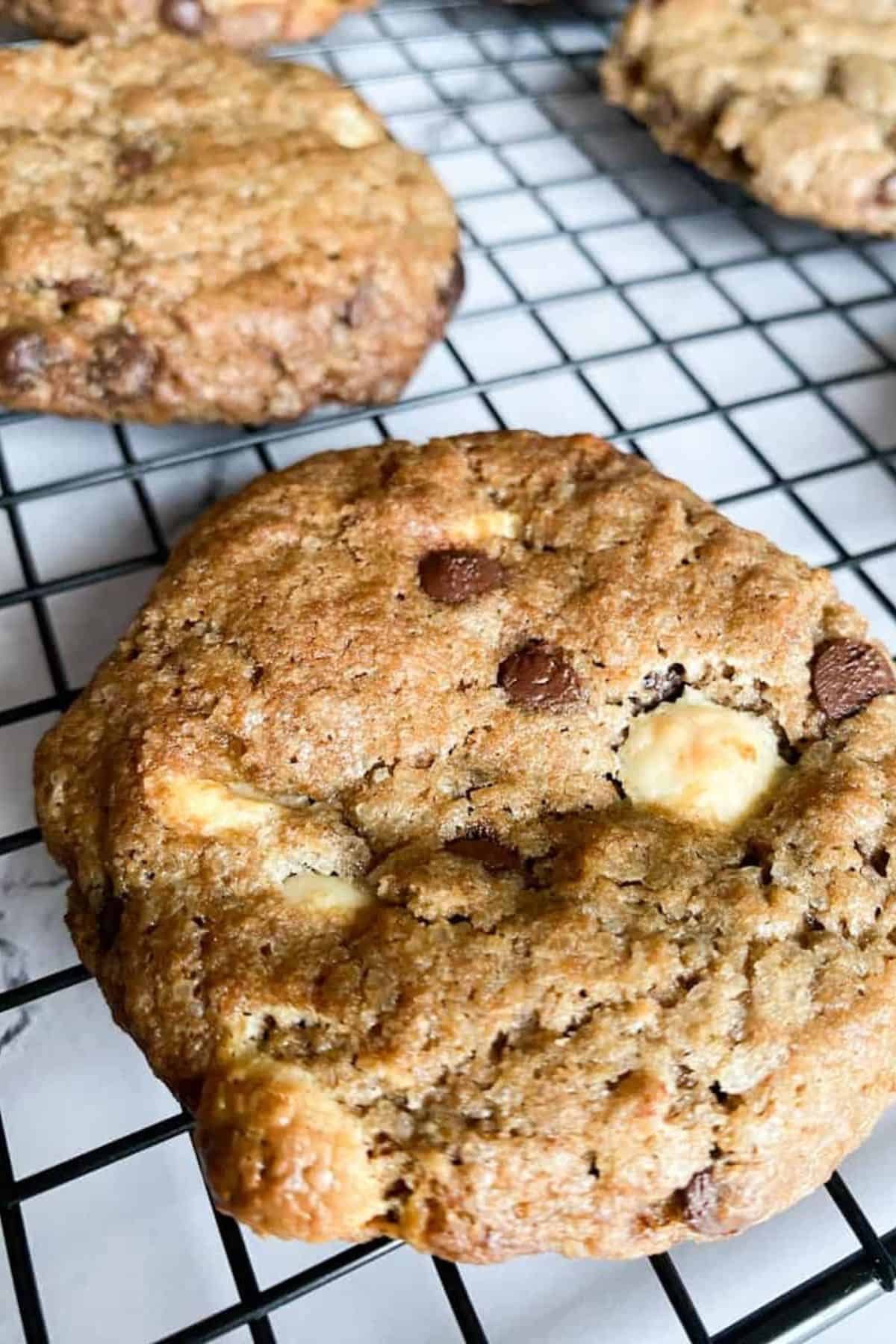 Close-up of a chocolate chip cookie resting on a wire cooling rack.