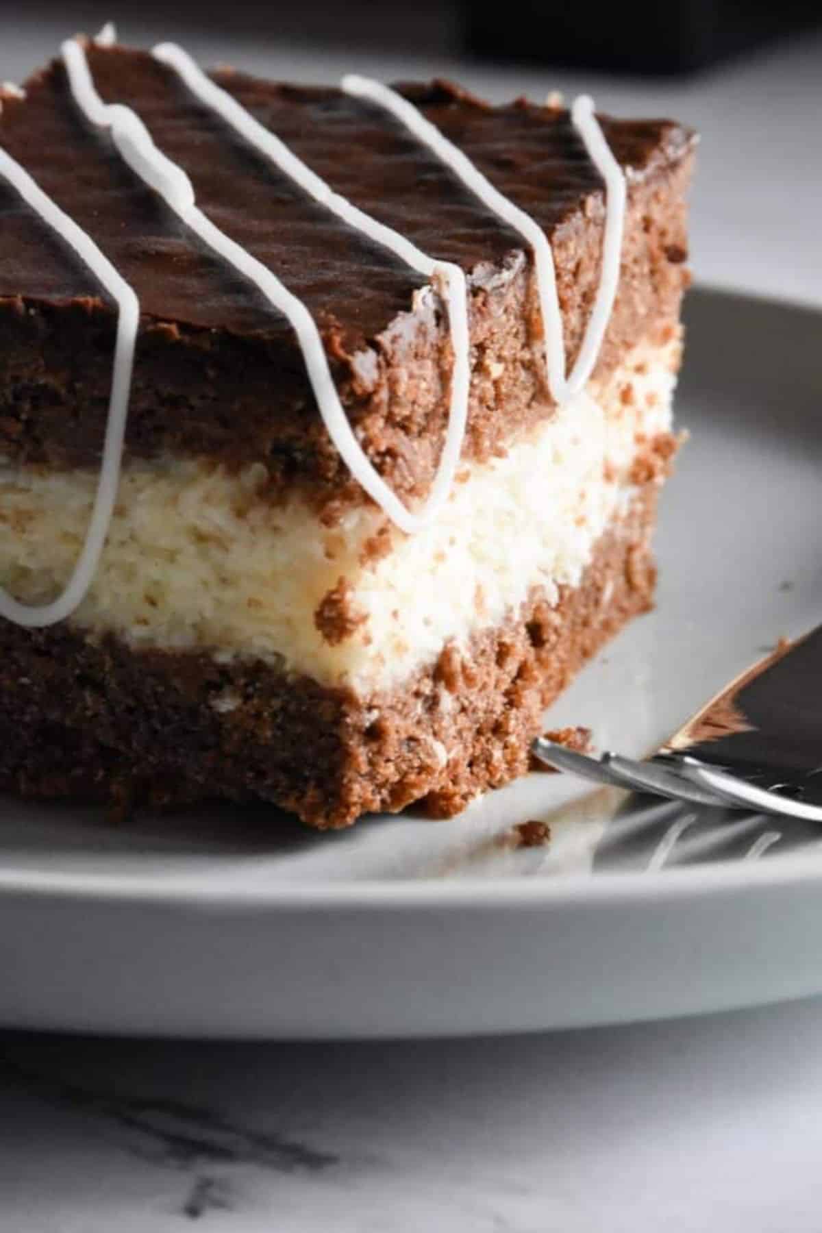 Sliced of sourdough discard chocolate coconut cake squares on a plate with a knife beside them.