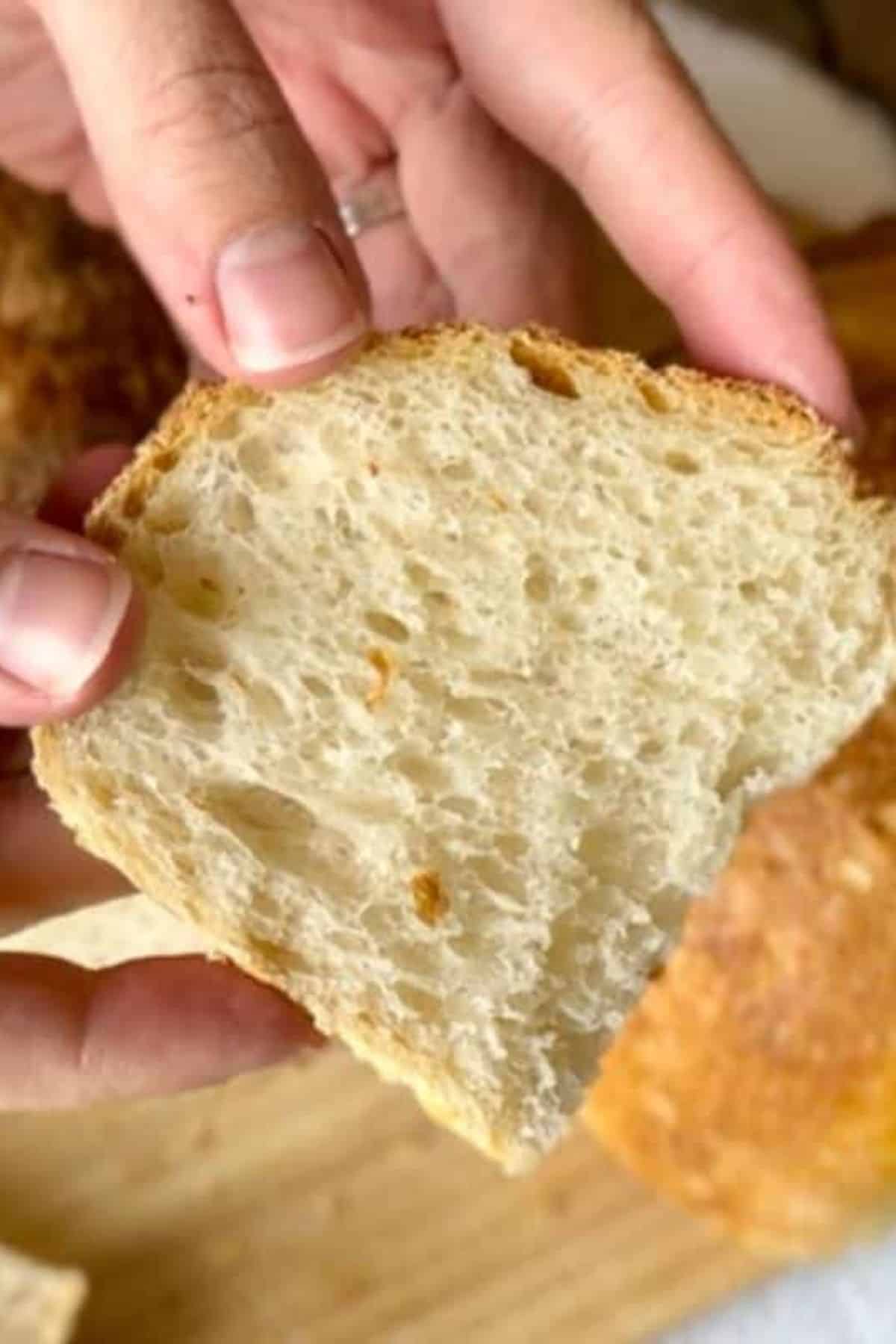 Single bread slice being held, revealing its soft, open interior.